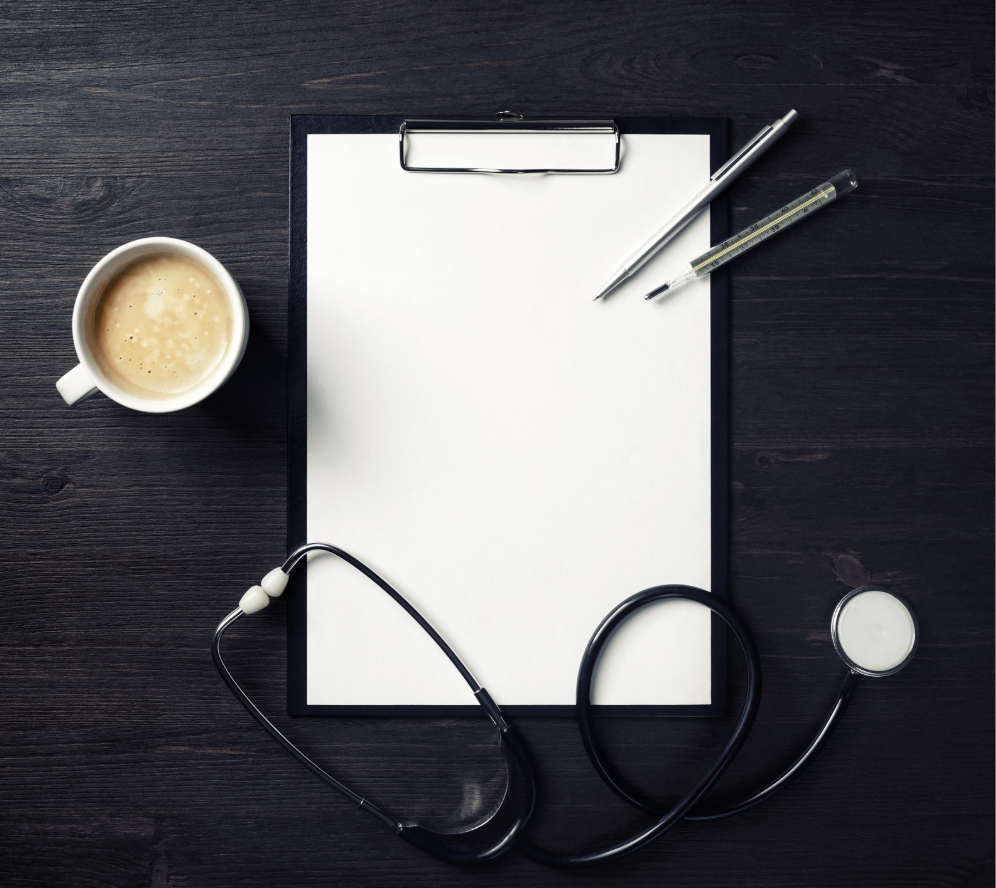 A clipboard, stethoscope, thermometer, pen and cup of coffee arranged on a dark timber desk
