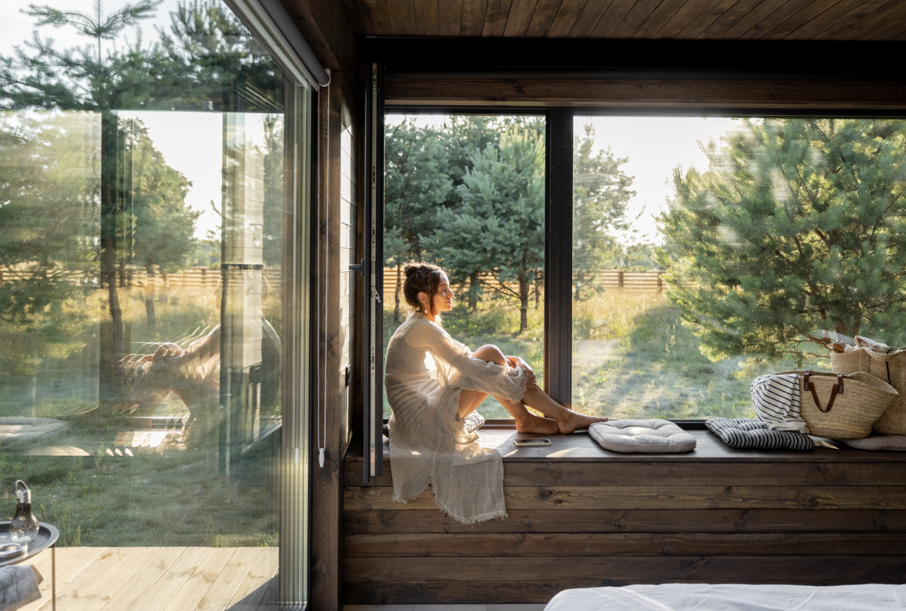 A woman sitting quietly beside an open window in warm natural light
